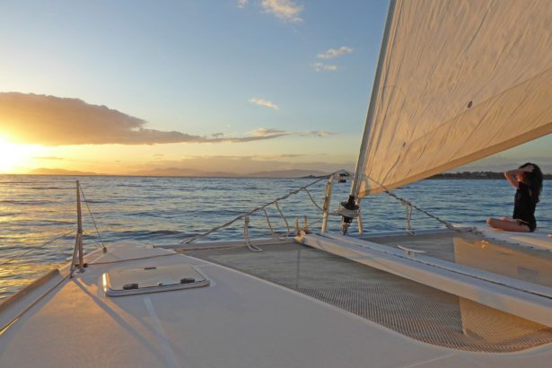 sailing athens in saronic gulf during sunset. Beautiful woman on catamaran boat on vacation.